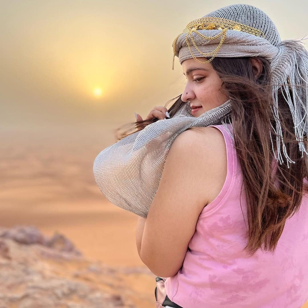 Priya watching the sunset over desert dunes